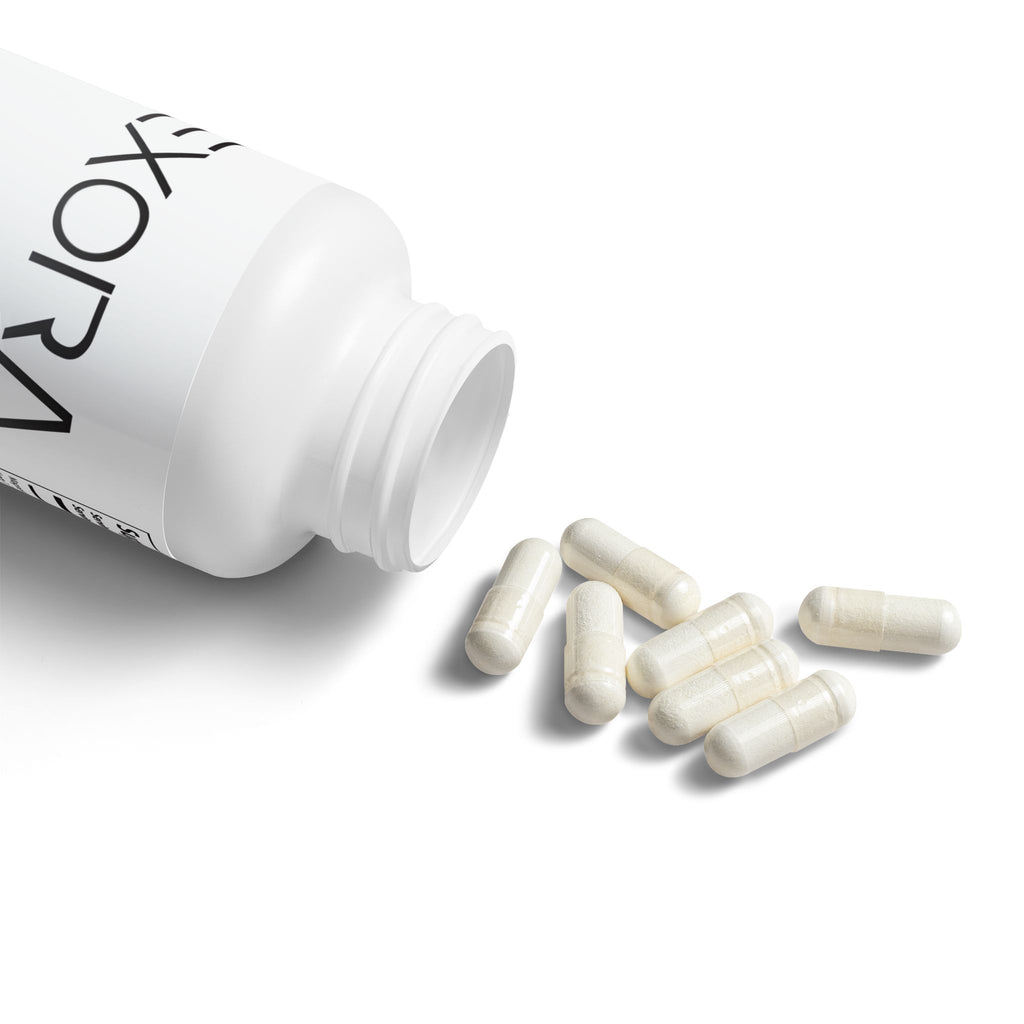 White bottle of 'EXORA' supplements with capsules spilling out on a white background