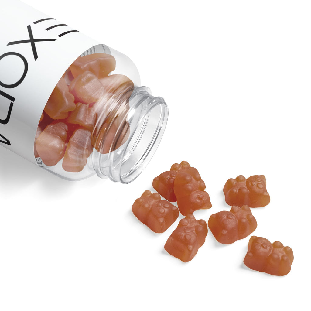 Clear jar with gummy bears spilling out onto a white background